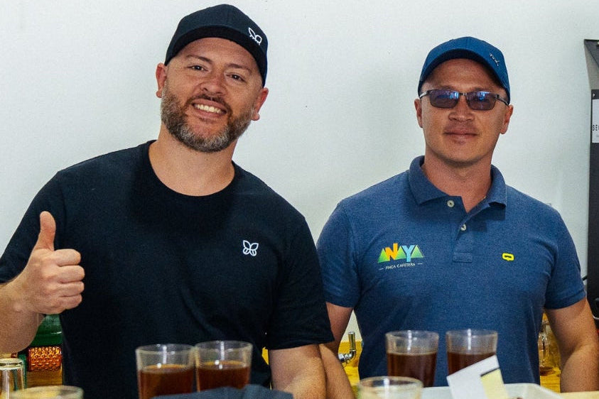 Maurizio, from Immigrant Culture and Sergio and friend from Finca Anaya standing behind a table with multiple glasses of coffee, in a coffee cupping setting