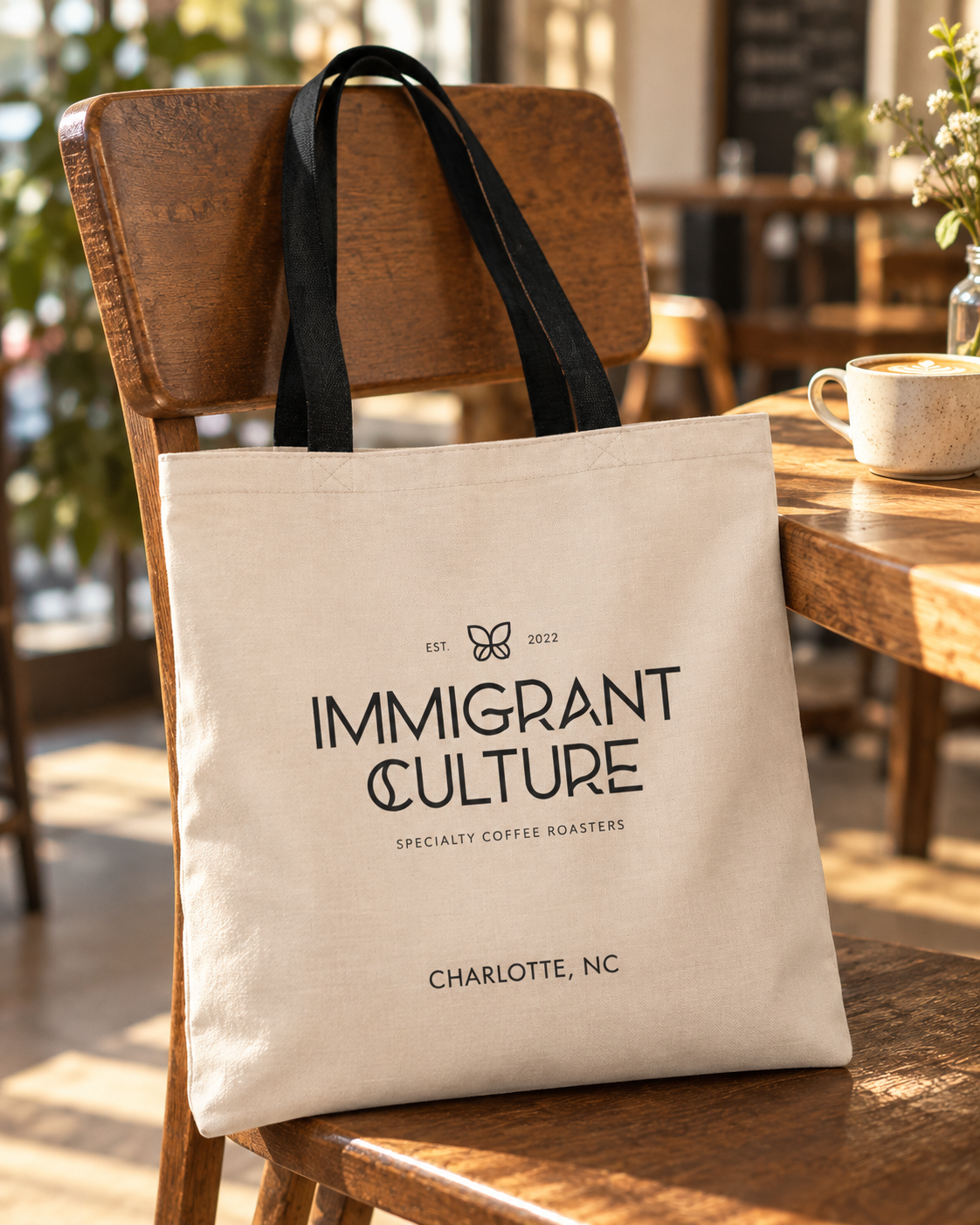 Immigrant Culture tote logo side on a cafe chair